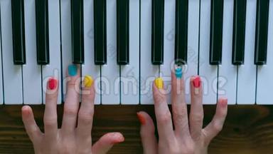 一个年轻积极的女孩，有漂亮的手和彩色指甲弹钢琴。